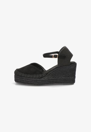 Sandalia espadrille de cuña negra con plataforma trenzada, puntera cerrada, correa en el tobillo y pequeña hebilla dorada.