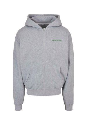 Szary rozpinany hoodie z miękkiego materiału, z przednią kieszenią, ściągaczami przy mankietach i dole oraz zielonym napisem na górze po lewej stronie klatki piersiowej.