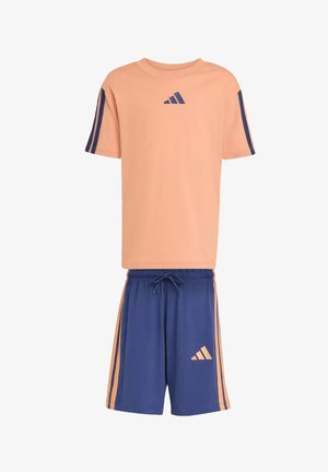T-shirt pesca a maniche corte con righe blu navy e logo abbinata a pantaloncini blu navy con righe pesca e logo coordinato.