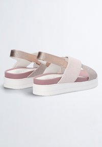 Alustavat sandaalit, joissa on elastiset hihnat beigeinä ja metallinhohtoisena ruusukultana. Varustettu tekstuuripinnalla ja vaaleanpunaisella pehmustetulla sisäpohjalla.