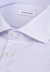 Chemise à motifs bleu clair avec un col structuré, dotée d'un petit bouton blanc et d'une étiquette indiquant "seidensticker". Tissu texturé.
