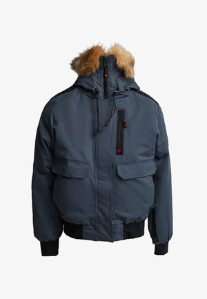 Navy blauwe gewatteerde jas met een bont gevoerde capuchon, dubbele voorzakken, een verticale ritszak en elastische manchetten en taille.