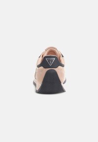 Scarpe da ginnastica rosa chiaro con accenti neri, materiale in suede, suola in gomma testurizzata e logo triangolare sul tallone.