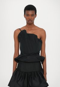 Black dress with asymmetrical, structured bodice and a pleated design. Features thin straps and a flared, ruffled skirt at the hem.