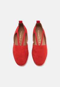 Paire de chaussures rouges en daim à enfiler avec des brides élastiques latérales et des semelles en jute cousues, vues de dessus sur fond blanc.