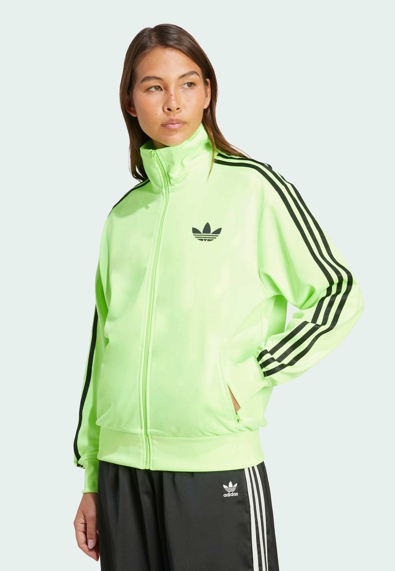 Neon-grüne Zip-Jacke mit schwarzen Streifen an den Ärmeln, ausgestattet mit einem schwarzen Logo auf der Brust. Glattes, leichtes Material.