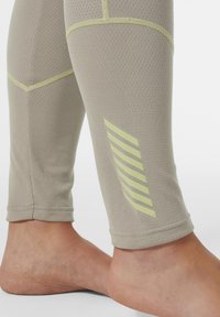Lichtbeige leggings van een gestructureerde stof, met gedempte gele steken en een gestreept ontwerp op de kuit.