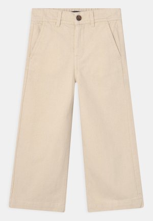 Vaaleanbeiget leveät housut, joissa on sivutaskut, vyölenkit ja ruskea nappikiinnitys vyötäröllä.