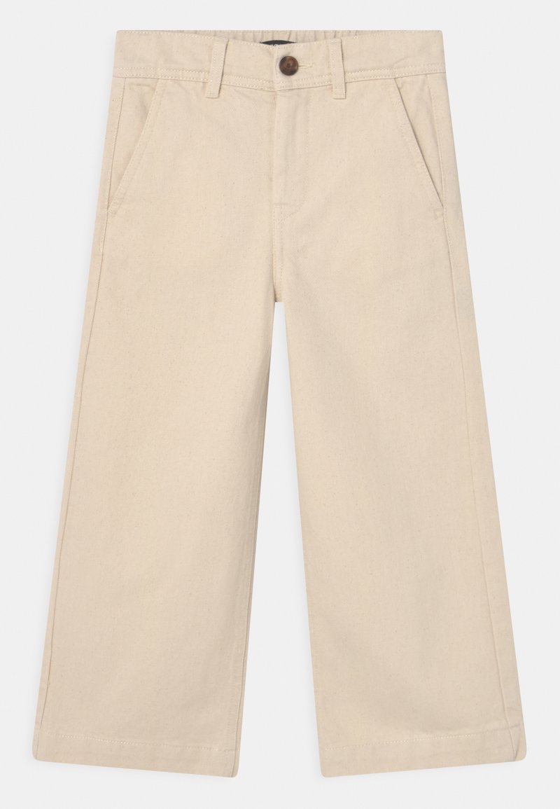 Pantalons larges beiges avec poches latérales, passants de ceinture et une fermeture à bouton marron à la taille.