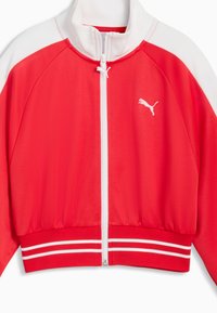 Červená atletická bunda s bielymi akcentmi, vysokým golierom, predným zipsom, rebrovaným lemom a pruhovanými manžetami. Na ľavej strane na hrudi je malá logo.