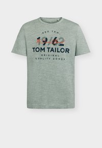 Πράσινο κοντομάνικο μπλουζάκι σε ελαφρύ υφή, με την επιγραφή "1962 TOM TAILOR ORIGINAL QUALITY GOODS" σε ναυτικό μπλε και κόκκινη εκτύπωση.