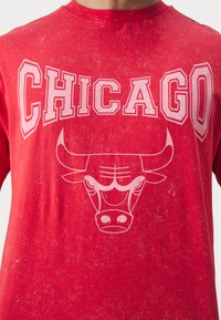 Maglietta di cotone rossa con la parola "CHICAGO" in lettere bianche in grassetto e un logo di un toro bianco con corna pronunciate e dettagli facciali evidenti.