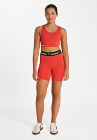 Roter Sport-BH und passende Shorts aus elastischem Stoff. Der BH verfügt über einen elastischen Markenbund, die Shorts sind tailliert geschnitten.