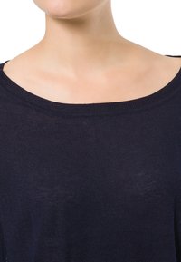 Marineblaue Strickoberteil mit weitem, rundem Ausschnitt; weiche Textur; minimale Nähte und Details; der Kragen liegt bequem auf den Schultern.