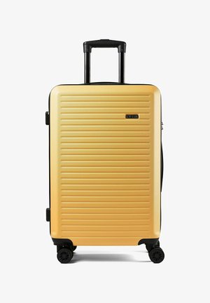 Gele harde koffer met horizontale ribbels, inklapbare zwarte handgreep, vier zwarte zwenkwielen en zijhandvatten.