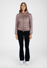 Giacca puffer color malva chiaro con design trapuntato orizzontale, cappuccio e zip frontale. Abbinata a pantaloni neri a zampa d'elefante e sneakers bianche.