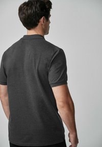 Kulfarvet polo shirt med korte ærmer, lavet af åndbart stof, med en ribbet krave og en lige skåret kant.