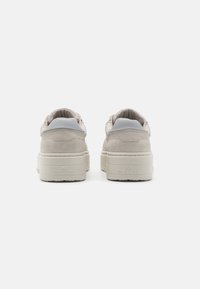 Gray suede sneakers with a white rubber sole, featuring a smooth back panel and subtle branding on the heel. Rounded shape, minimalistic design.