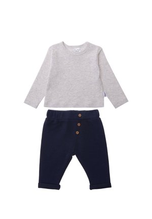 Graues Langarmshirt mit Rundhalsausschnitt und Schulterknöpfen, kombiniert mit navyfarbenen Hosen mit umgeschlagenen Säumen und drei Holzknöpfen.