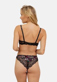 Soutien-gorge en dentelle noire avec des bretelles réglables et un bord festonné, associée à une culotte colorée à motifs avec une finition en dentelle et un design floral.