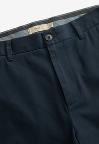 Pantaloni slim fit de culoare bleu marin, confecționați dintr-un material texturat, cu închidere frontală printr-un nasture și un model discret în carouri pe talie.