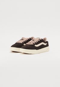 Black suede sneakers with light pink laces, featuring a white wave design on the sides and a thick cream-colored rubber sole.