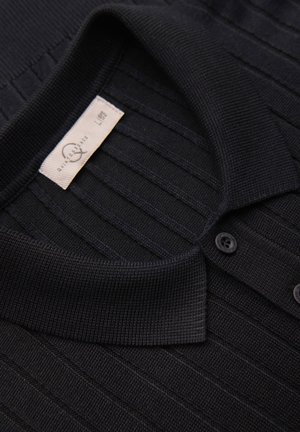 Sort ribstrikket poloshirt med en foldet krave, to knapper og en synlig størrelse- og vaskeanvisningslabel inde i nakken.