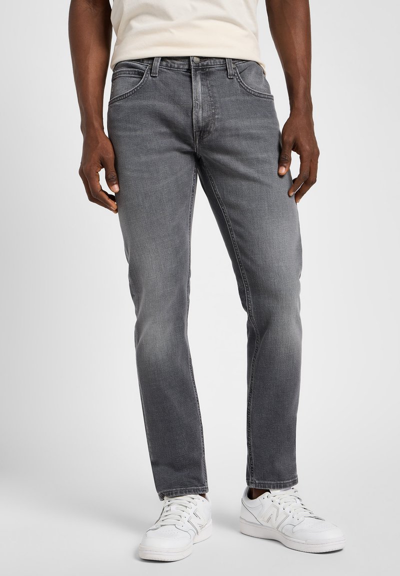 Grey denim jeans with a straight fit, subtle fading, five-pocket design, and metal hardware accent. Paired with white athletic sneakers.
