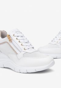 White sneakers featuring a mesh upper with gold accents and zip closure, rounded toe, and thick rubber sole. Smooth texture overall.