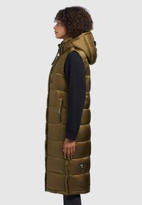 Olive green puffer vest with a hood, zippered front, side pockets, and quilted pattern, worn over a black long-sleeve top.