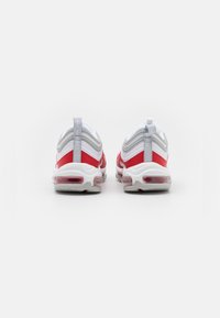 Scarpe da ginnastica rosse e bianche con un design elegante, caratterizzate da una superficie texture, ammortizzazione ad aria visibile e un laccio posteriore grigio.