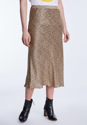 Jupe midi à imprimé léopard portée avec un haut blanc et des bottines en cuir noir à talons carrés.