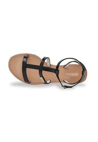 Black leather sandal with thin straps, a flat sole, and a light tan insole featuring stitching detail. Adjustable ankle strap with hardware.