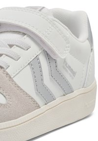 Weißer und grauer Sneaker mit Obermaterial aus Wildleder und Synthetik, Klettverschluss, genähten Details und einer strukturierten Gummisohle mit dezentem Muster.