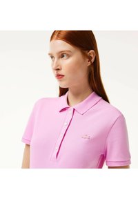 Polo shirt rosa in cotone, con colletto classico, patta con bottoni e un piccolo logo ricamato sul petto.