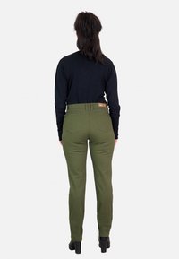 Pantalones verde oliva con un diseño ajustado y una cintura alta, que cuentan con un detalle de bolsillo trasero y una etiqueta de cuero marrón en la cinturilla.