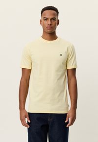 Κίτρινο κοντομάνικο μπλουζάκι από βαμβάκι, με στρογγυλή λαιμόκοψη και μικρό πράσινο λογότυπο "II" στο αριστερό στήθος. Απλό σχέδιο.