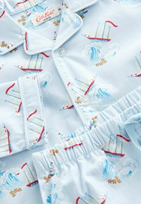 Conjunto de pijama de algodón de color azul claro que presenta un patrón de velero y olas en rojo, blanco y azul, con cierre de botones y cinturilla elástica.
