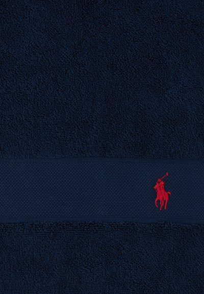 Tela texturizada azul marino con una banda horizontal que presenta un pequeño logo bordado en rojo de un jugador de polo a caballo.