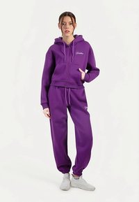 Fioletowa bluza z kapturem na suwak oraz pasujące dresy wykonane z miękkiego materiału, z prążkowanymi mankietami, talią ze sznurkiem i haftowanymi logo.