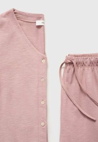 Ljusrosa hemmakläder i set som har en v-ringad topp med fem knappar och byxor med snörning och resårmidja. Mjuk tygtextur.