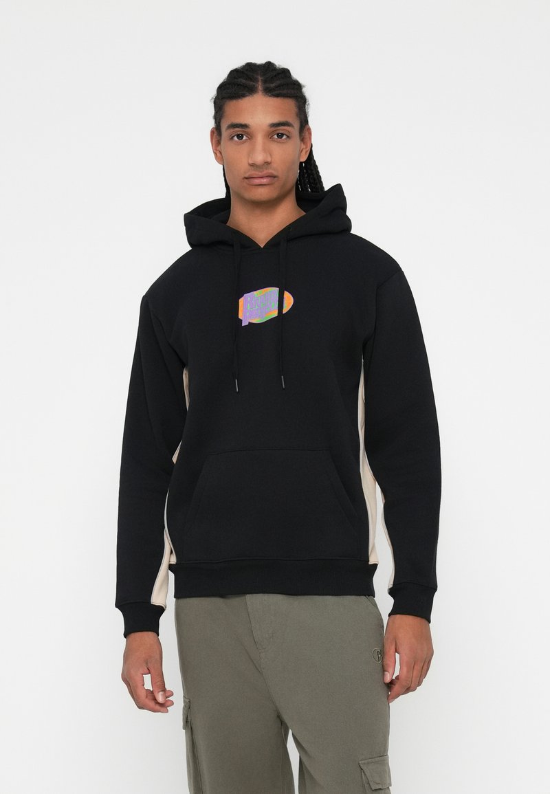 Zwarte hoodie met een gestructureerde grafiek op de borst, contrasterende tan zijpanelen en een kangaroo-pocket.