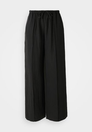 Zwarte wijde pantalon van textuurstof. Ze hebben een rekbare tailleband met een trekkoord en verticale plooien voor extra detail.