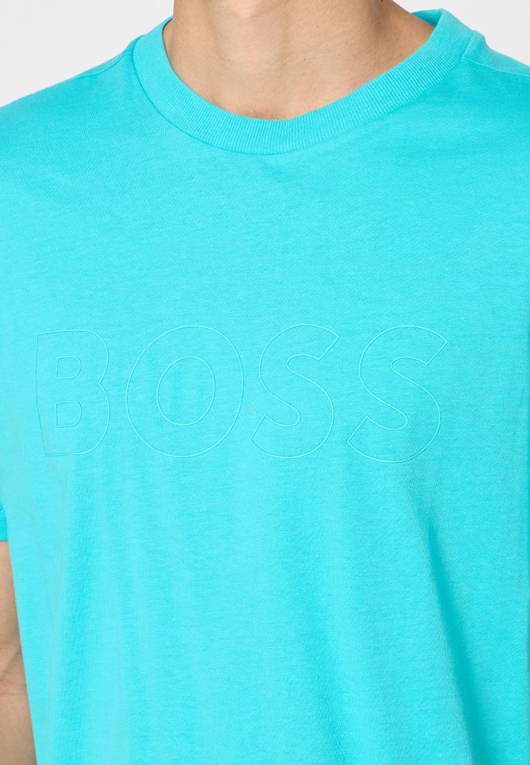 T-shirt in cotone turchese con collo a giro, maniche corte e un discreto logo "BOSS" in rilievo sul fronte. Texture liscia.
