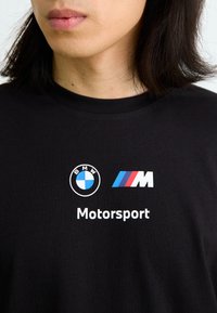 Sort bomulds T-shirt med BMW-logoen, et farvet M badge og ordet "Motorsport" trykt i hvidt nedenunder.