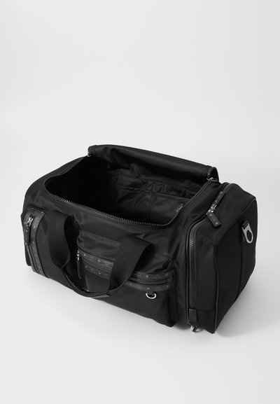 Black duffle bag made of durable fabric; features multiple zippered pockets, sturdy handles, and a spacious, open interior.