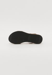 Sole in gomma nera con scanalature testurizzate; presenta il marchio e il numero di modello; forma curvata con una leggera elevazione nel tallone.