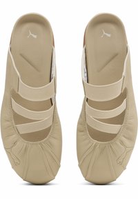 Μπεζ παπούτσια Puma slip-on με τρεις ελαστικές λωρίδες, λεπτομέρεια μαζεμένου δακτύλου και λογότυπο Puma στο δάχτυλο και στην πάτημα.
