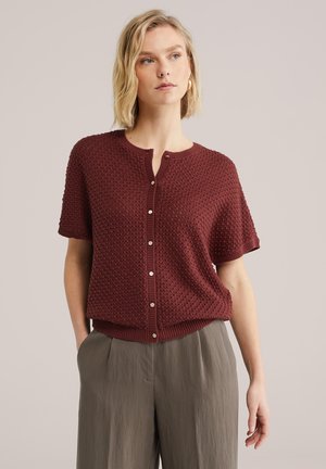 Bordový pletený sveter s textúrovaným vzorom, krátkymi rukávmi, zaokrúhleným výstrihom a zapínaním na gombíky vpredu. Pevný rebrovaný lem.