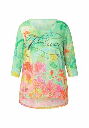 Túnica ligera verde con cuello redondo, mangas 3/4, patrones florales en rosa y naranja, y el texto "Paz" adornado con purpurina.
